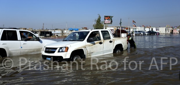 An Iraqi man pushes a vehicle through flooded streets in Baghdad's Sadr City neighbourhood. (© Prashant Rao for AFP)